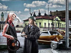På bilden syns en iscensatt situation. I bakgrunden har en en bil kört in i en lyktstolpe. En ung reporter i kappa och grön filthatt intervjuar chauffören som håller i en ratt och har ett bandage runt huvudet. Båda ser glada ut och det är tydligt att situationen är fiktiv.