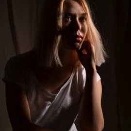 En ung kvinna med axellångt blont hår fotograferad i motljus.