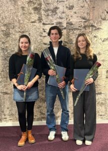 Tre unga studeranden står i rad med rosor och diplom i handen.