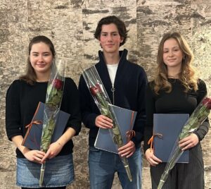 Tre unga studeranden står i rad med rosor och diplom i handen.