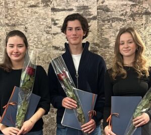 Tre unga studeranden står i rad med rosor och diplom i handen.
