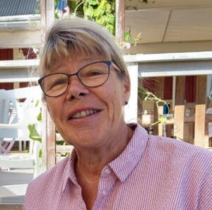 En äldre dam ler mot kameran.