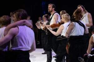 Bilden föreställer musikanter som spelar gitarr och fiol och sjunger.