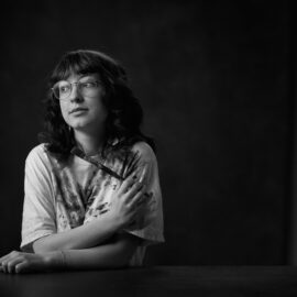 En svartvit bild på en ung tjej som sitter med en pensel i handen.