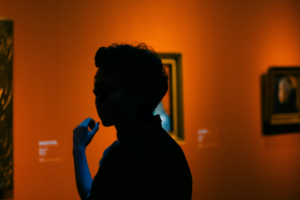 En person står och beundrar verk på en utställning på Ateneum.